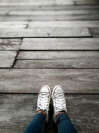 Low section of woman wearing shoes on wooden floor