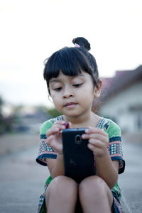 Girl using phone against clear sky