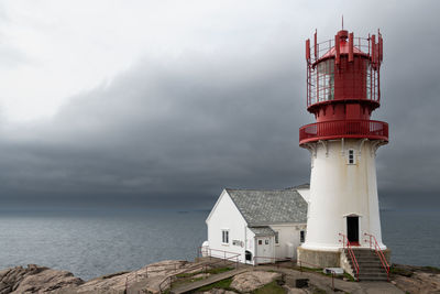 Lighthouse by sea against sky