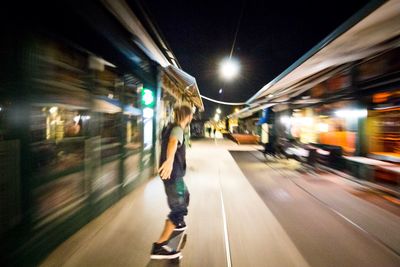 Blurred motion of man walking on illuminated street at night