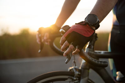 Midsection of man riding bicycle on road during sunset