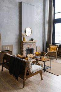 Scandinavian-style interior with fireplace, rattan chair in the trendy colors of 2021 gray yellow