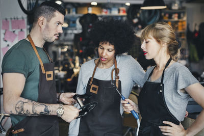 Multi-ethnic mechanics holding tools in workshop