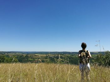 Full length of woman standing on field against clear blue sky