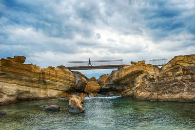 Arch bridge over river against cloudy sky