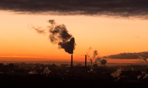 Smoke emitting from chimney against sky at sunset