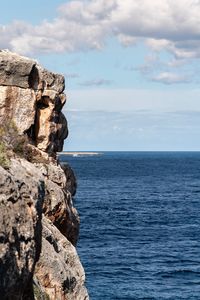 Rock formation by sea against sky