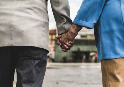 Midsection of couple holding hands