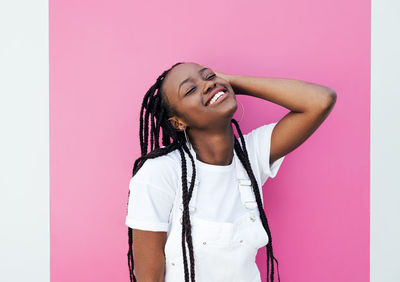 Portrait of young woman standing against yellow background