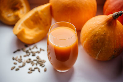 A glass of pumpkin juice with pumpkin seeds on a windowsill