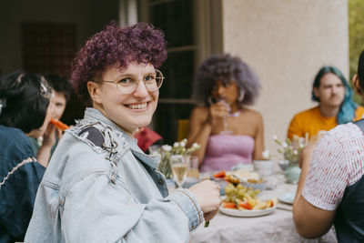 Side view portrait of happy non-binary person with friends during party in back yard