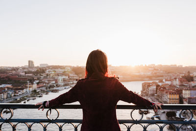 Back view of relaxed woman in porto bridge at sunset. tourism in city europe. travel and lifestyle