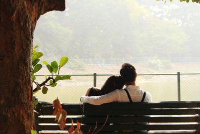 Rear view of couple sitting on bench in park