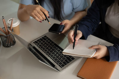 Midsection of man using mobile phone while sitting on table