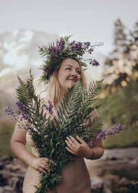 Beautiful woman standing by purple flowering plant