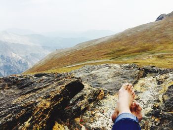 Low section of man on mountain against sky