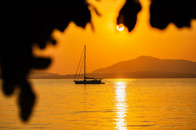 Silhouette sailboat in sea against sky during sunset