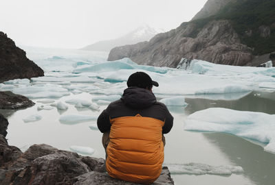Rear view of man looking at lake during winter