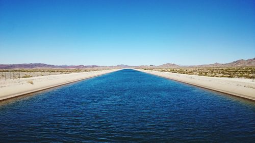 Scenic view of calm river against blue sky