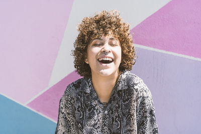 Portrait of smiling young woman looking away against wall