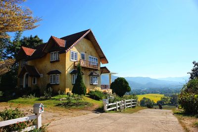 House amidst trees and buildings against clear blue sky