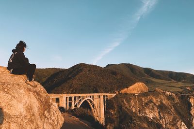 Woman on bridge by mountains against sky