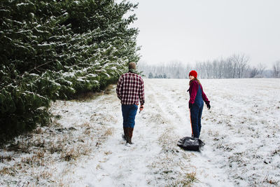 Rear view of woman walking on snow covered field