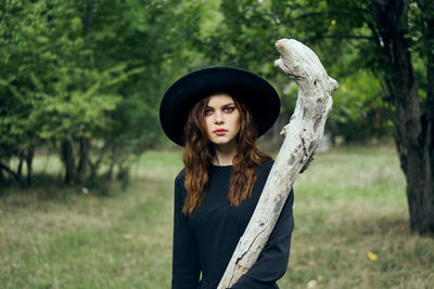 Portrait of young woman standing against trees