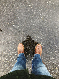 Low section of man standing on wet footpath