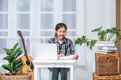 Young woman using phone while sitting at home