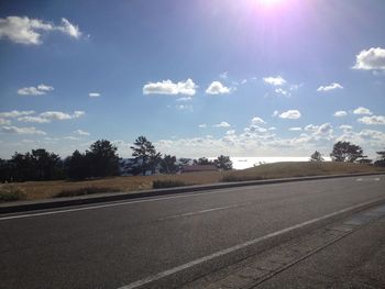 Road by trees against sky
