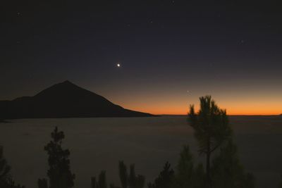 Scenic view of silhouette mountains against sky at night