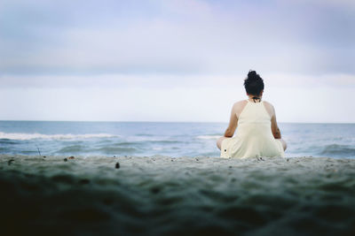 Rear view of woman sitting on beach