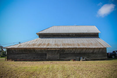 Barn on field against blue sky