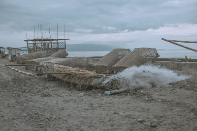 Fishing equipment on shore at beach against sky