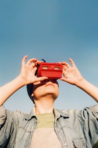 Midsection of man using mobile phone against blue sky