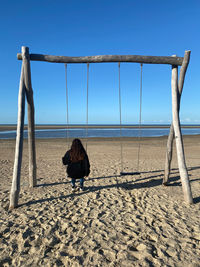 Rear view of woman on beach against sky