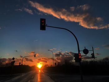 Road sign against sky at sunset