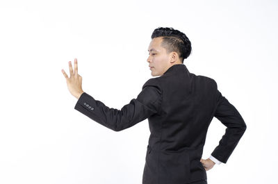 Midsection of man with arms raised standing against white background