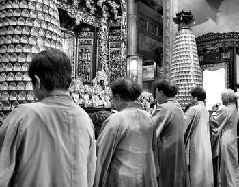 Rear view of people walking outside temple in city