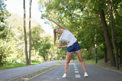 Side view of woman walking on road along trees