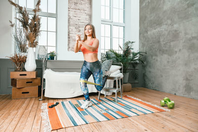  the athlete lunges with sport fitness rubber bands in the background there is a bed, a vase