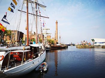 Sailboats moored at harbor against sky