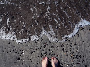 Low section of woman standing on sand