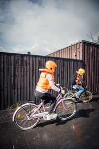 Siblings riding bicycle on road