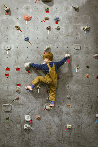 Rear view of boy climbing wall at health club