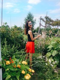 Portrait of young woman standing against plants