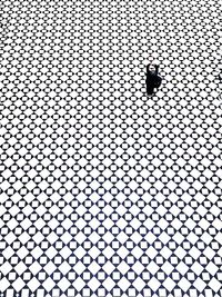 Person standing on checked tiled with arms raised