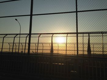 Chainlink fence against sky at sunset