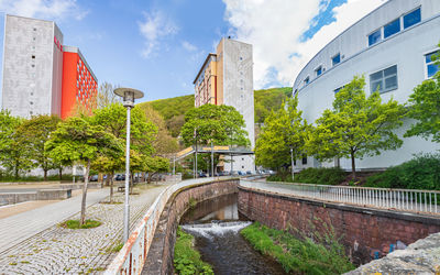 Road by buildings in city against sky